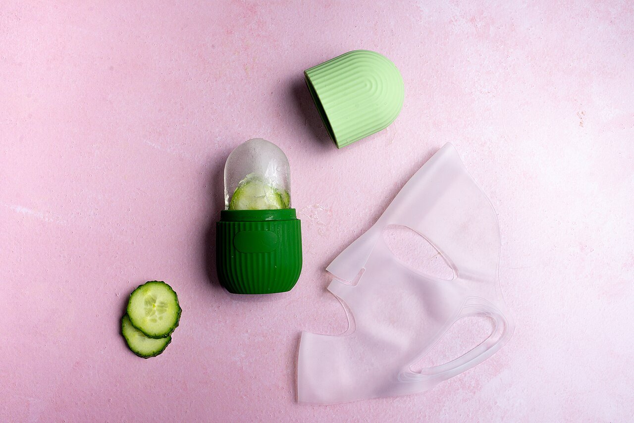 Cucumber slices beside a green facial mask and skincare applicator