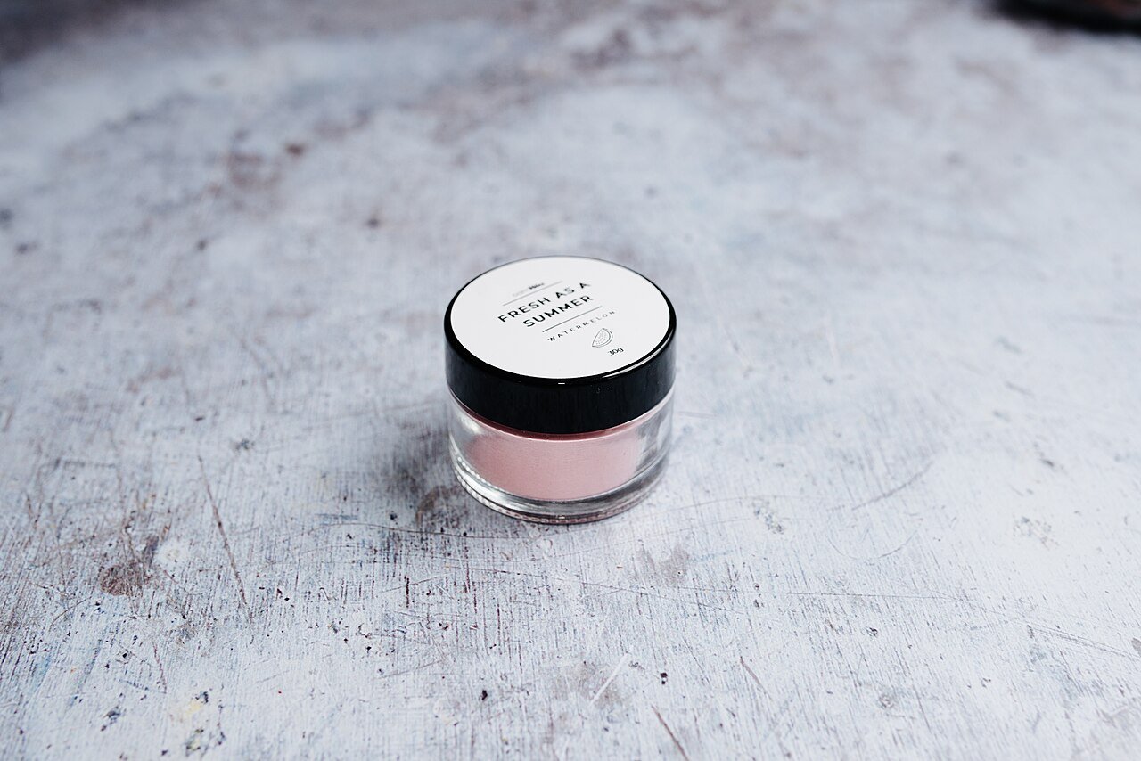A jar of rich pink night cream on a textured background